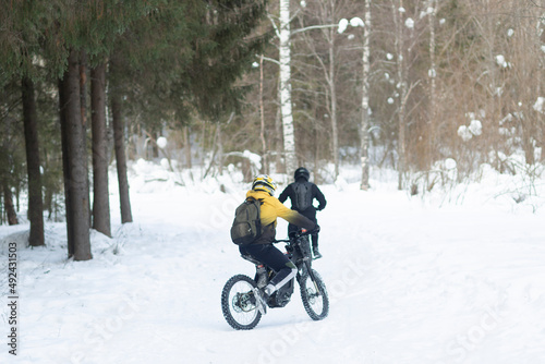 People ride electric motorcycles in winter on a winter road.