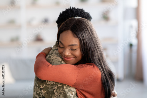 Reunion Concept. Beautiful Happy Black Woman Embracing Military Husband At Home photo