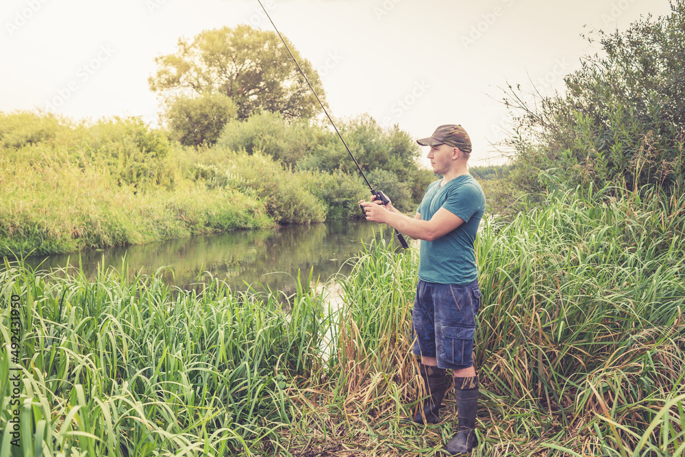 Fototapeta premium Fisherman on the river at dawn in summer.