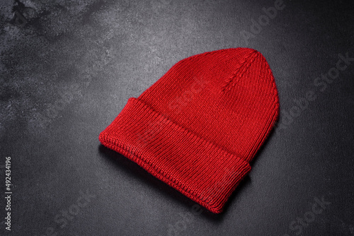 Red warm knitted women s hat on a concrete background