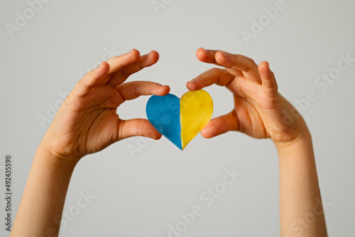 A heart-shaped badge depicting the State Flag of Ukraine as a symbol of patriotism and pride in one's country. State symbol of Ukraine in children's hands