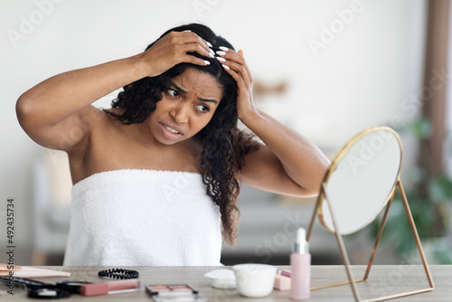 Upset young african american woman checking her hair photo