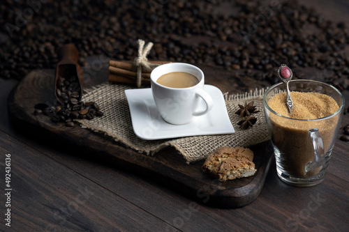 Composition with cup of espresso coffee with coffee beans and brown sugar on dark background