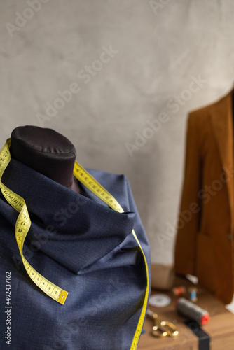 Cloth fabric at tailor mannequin and tape measure. Concept of clothes atelier