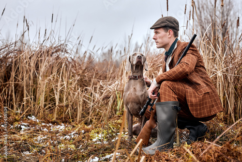 Hunting period, autumn season open. shikari with gun in suit in the autumn forest in search of a trophy. A man stands with weapons and hunting dog tracking down the game. outdoor portrait photo