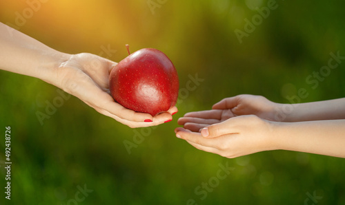 podziel się posiłkiem, kobieta podaje dziecku jabłko