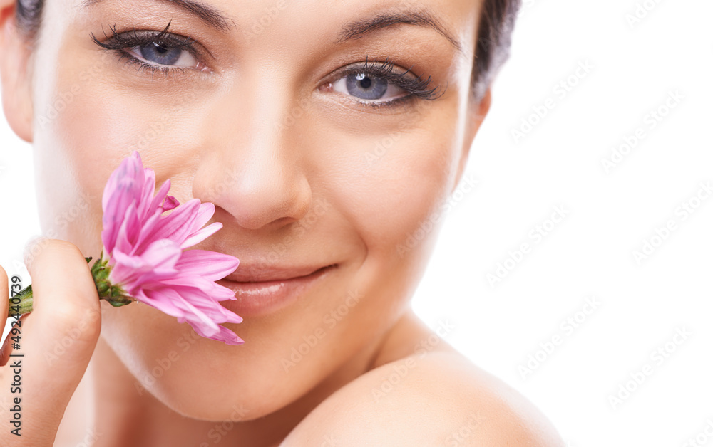 Fresh as a flower. A lovely young woman smiling at the camera while sniffing a pink flower.