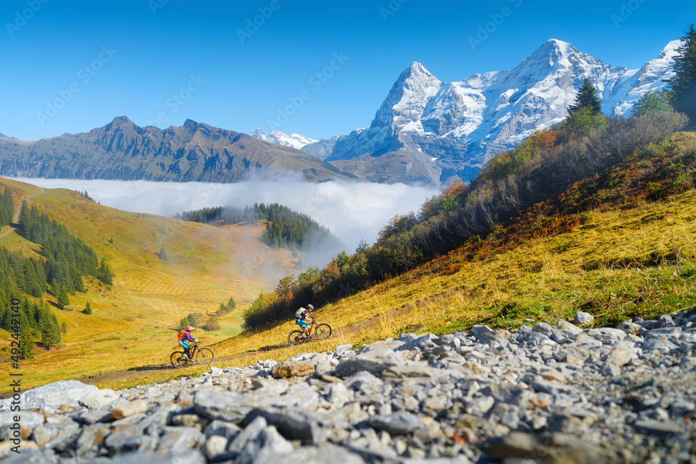 Two people riding bicycles in the mountains. A team sport. Cyclists in a mountain valley in the Alps. Traveling on a bicycle. High resolution picture for the background.