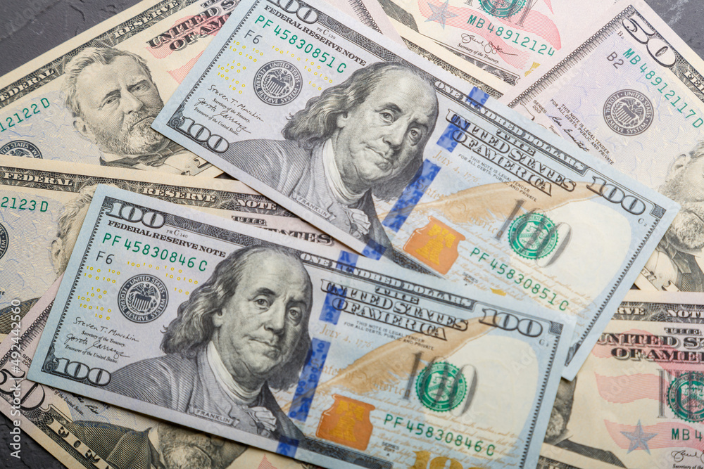 Fifty and hundred dollar bills are scattered on a flat surface in disarray. Fifty and hundred dollar bills are scattered on a flat surface in disarray.