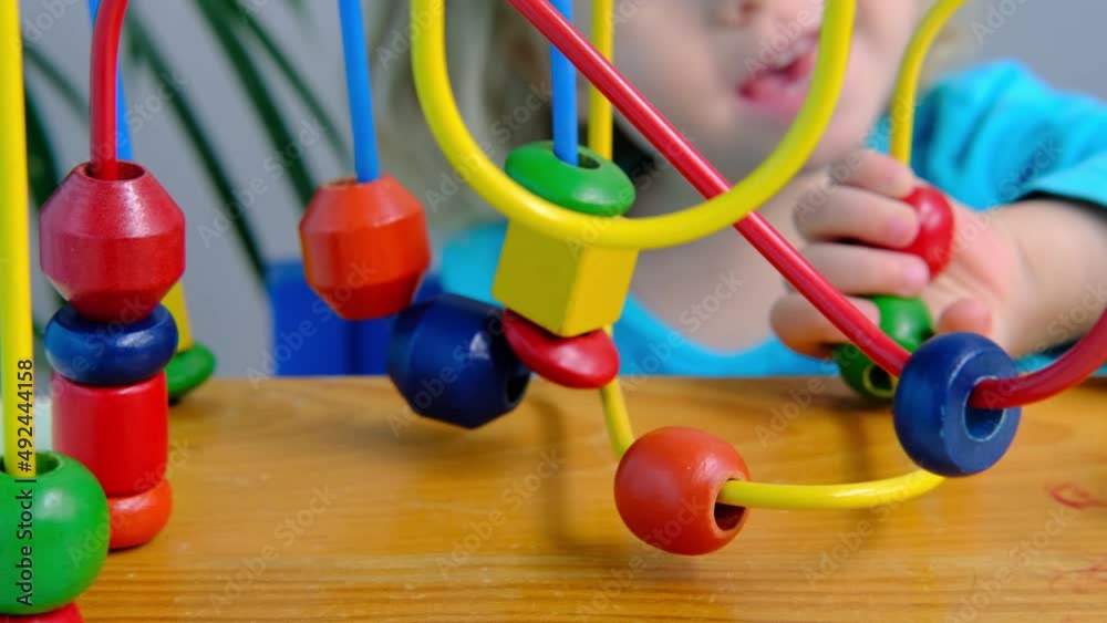 close-up smart little child, a blonde girl 2 years old playing with educational toy, looks through children's wire maze, concept childhood, early training, development of fine motor skills, thinking close-up smart little child, a blonde girl 2 years old playing with educational toy, looks through children's wire maze, concept childhood, early training, development of fine motor skills, thinking