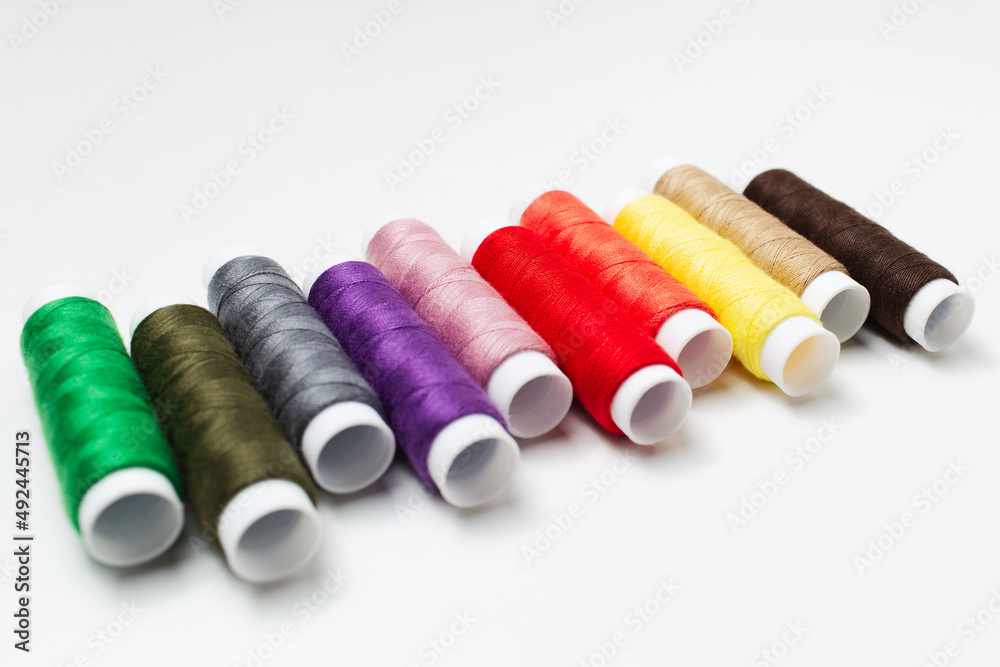 Close-up of colourful thread spools on white table. Close-up of colourful thread spools on white table.