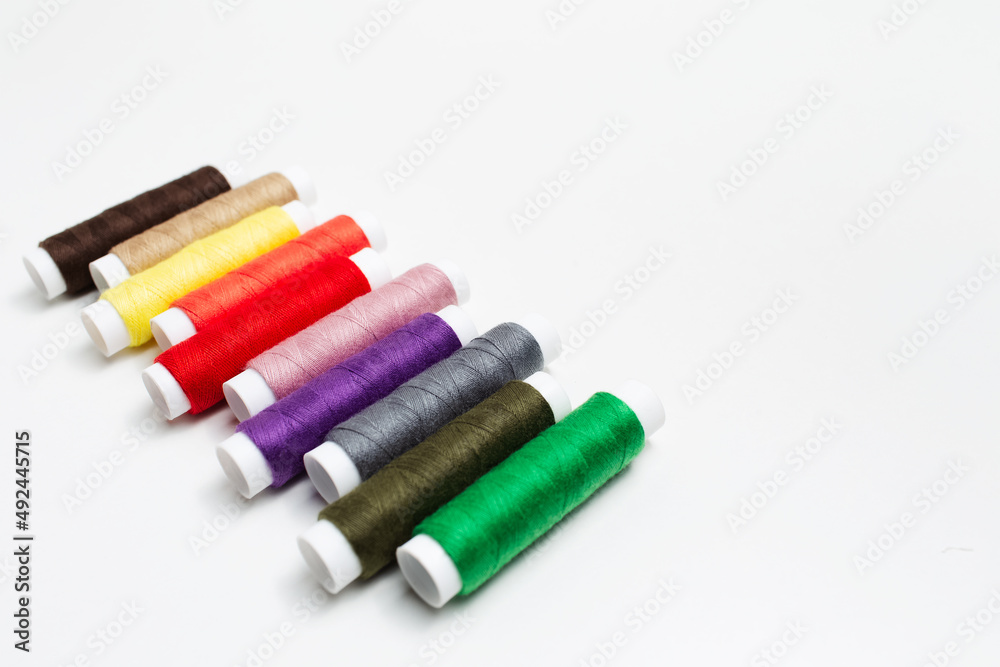 Close-up of colourful thread spools on white background. Studio photo. Close-up of colourful thread spools on white background. Studio photo.