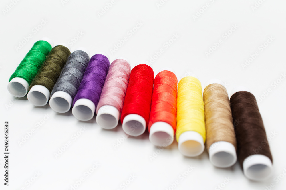 Close-up of colourful thread spools on white background. Plastic bobbins. Close-up of colourful thread spools on white background. Plastic bobbins.