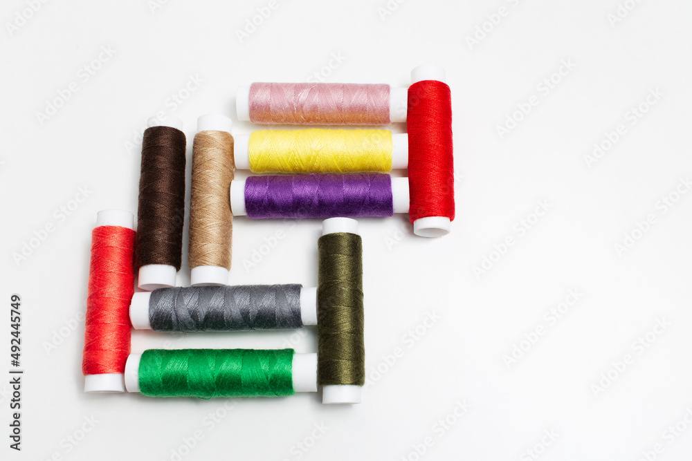 Close-up of colourful set of thread spools on white background. Close-up of colourful set of thread spools on white background.