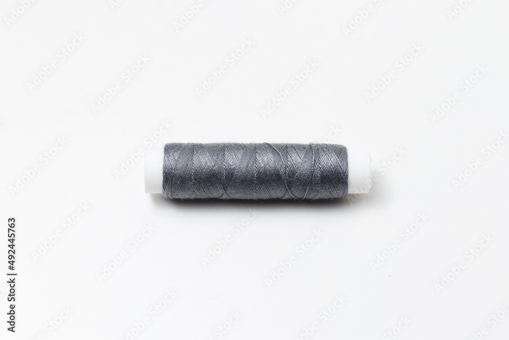 Close-up of grey thread spool isolated on white background.