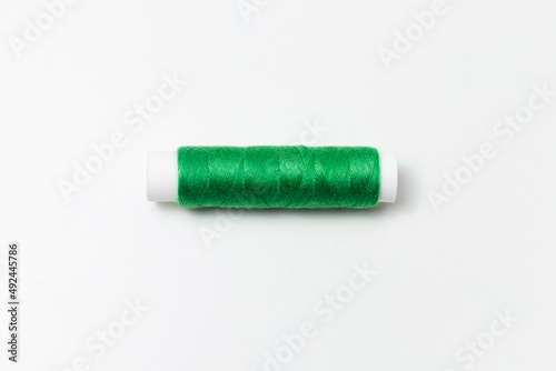 Close-up of green thread spool isolated on white background.