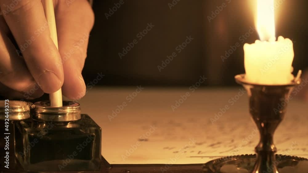The focus of this 1700s scene is on an inkwell into which a man is dipping his quill pen to get ink for writing his letter.