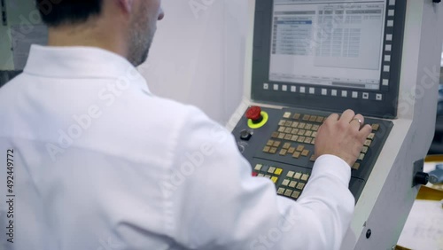 An engineer at an industrial plant. A worker controls the operation of a CNC milling machine. Tablet computer in hand. Drill manufacturing plant.