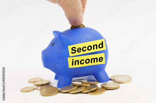 On the table are coins and a blue piggy bank with the inscription - Second income photo