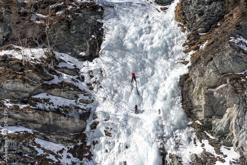 Ice climbers in Switzerland on a frozen waterfall in winter © Adrien