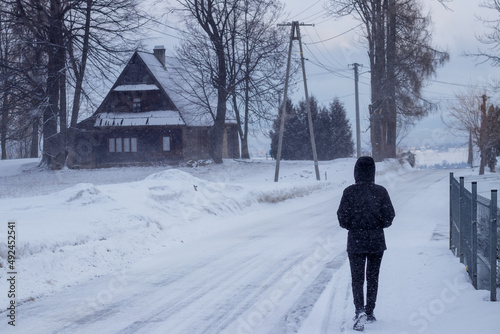 a person walking on a street covered with snow with a hut in the way