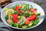 Salad with salmon and avocado on a dark background.
