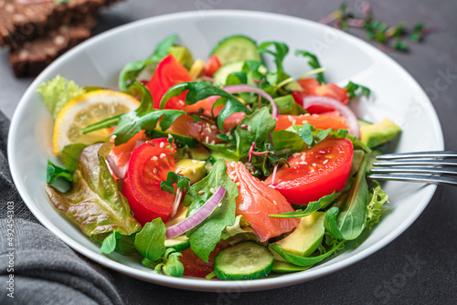 Salad with salmon and avocado on a dark background.