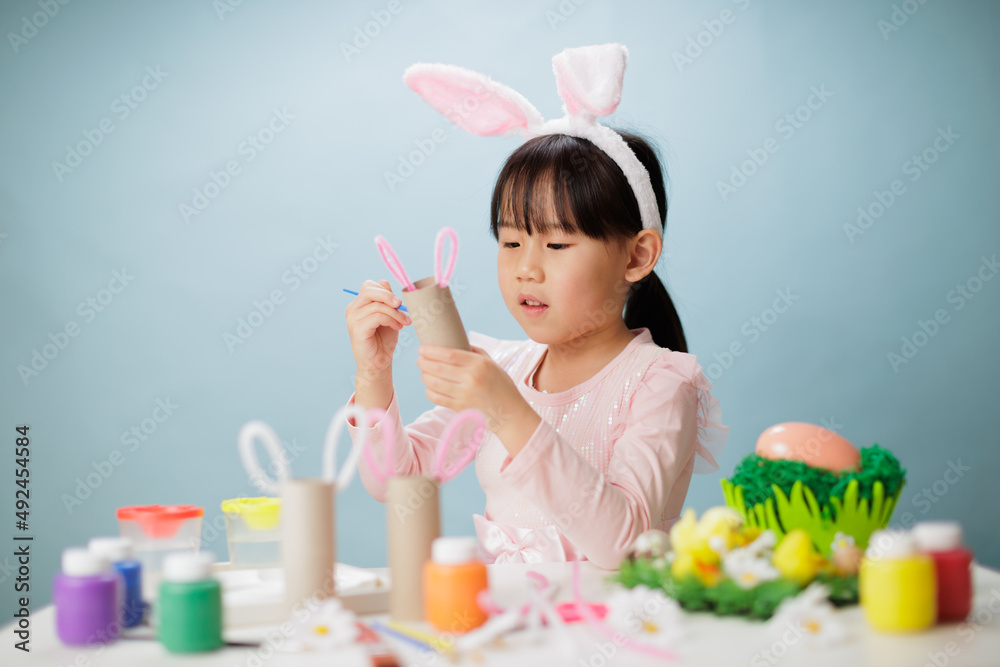 young girl making easter craft against plain background young girl making easter craft against plain background