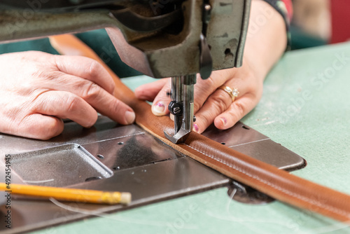 Handmade leather handle is skillfully guided by the hands of production worker at the factory