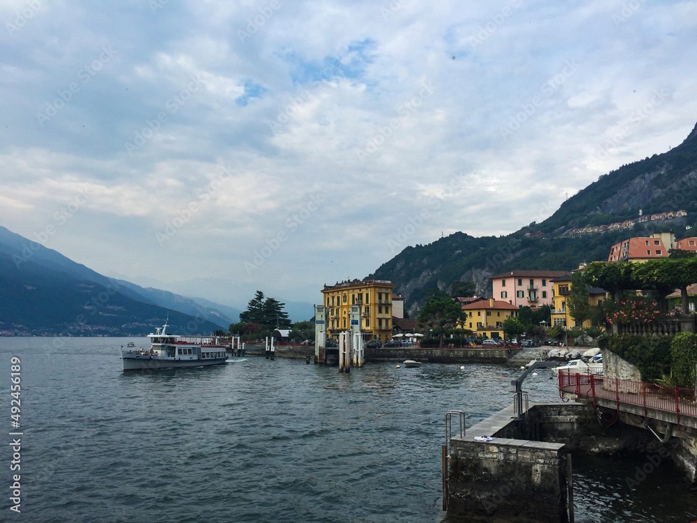 Varenna, Como lake, Italy. Colourful village by the Como lake, pier, mountain, park, boats and ferry. Evening sky, sunset. Horizontal