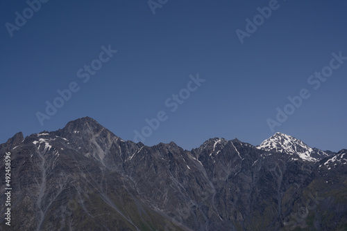 dramatically dark gray mountains with a bit of white snow on the tops, behind which a dark blue sky opens
