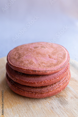 pila de 3 hot cakes esponjosos sabor fresa integral sobre base de madera circular y fondo claro photo