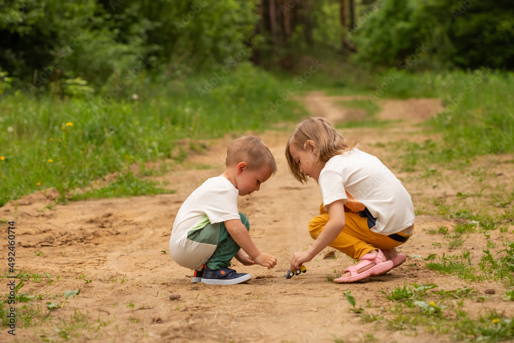 Fototapeta premium Little boy and girl play outdoors in the forest in summer