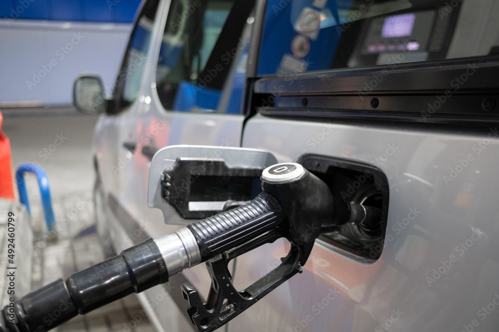 Gas station gun in the neck of the gas tank. Selective focus. The diesel fuel nozzle is inserted into the car's fuel filler neck. The concept of the global fuel crisis. 