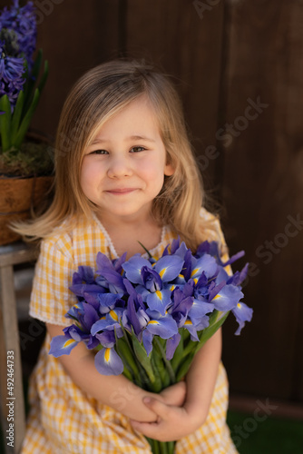 A girl in a yellow dress with iris flowers bouquet