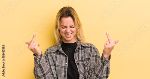 blonde caucasian woman feeling provocative, aggressive and obscene, flipping the middle finger, with a rebellious attitude