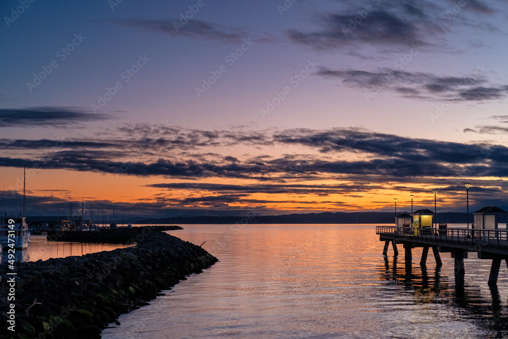 A fishing pier and marina at sunset, with clouds in the sky