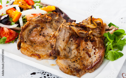 Roasted pork steak with vitamin vegetable salad and leaves of cornsalad..