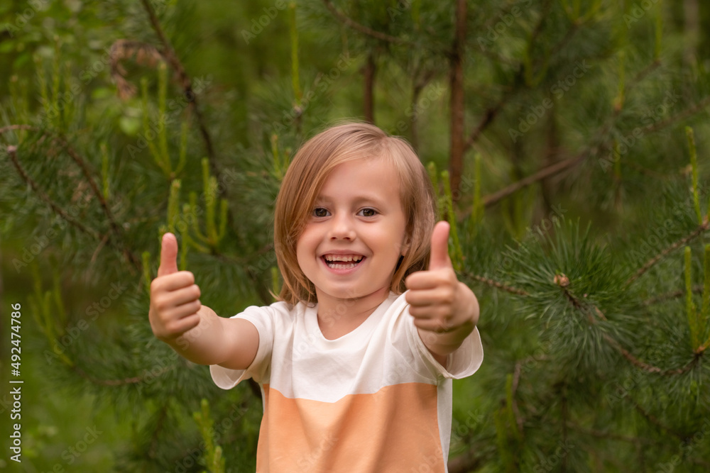 Blond charming caucasian girl in casual closing showing thumb up in the forest Blond charming caucasian girl in casual closing showing thumb up in the forest