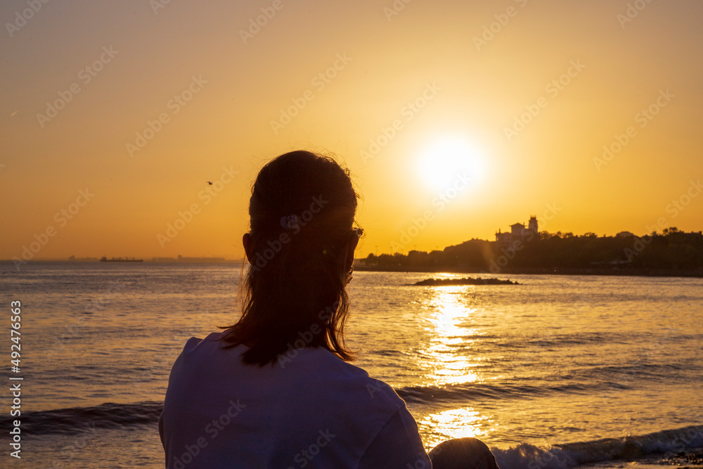 woman sitting and watching sunrise on a bench. woman sitting and watching sunrise on a bench.