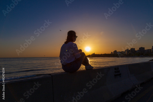 woman sitting and watching sunrise on a bench. © Birol
