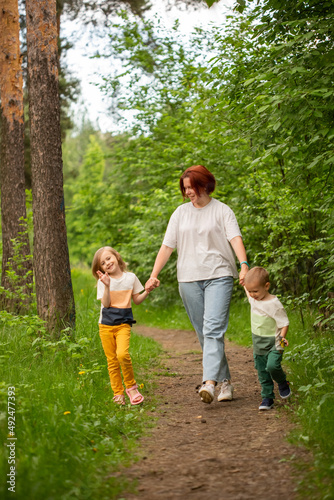 Mom walks with two children in the summer in the forest