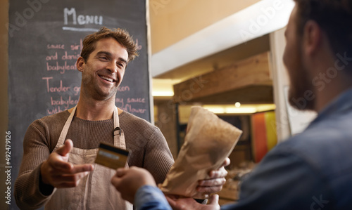 The customers keep coming back for more. Shot of a handsome young man making a sale at his food stall.