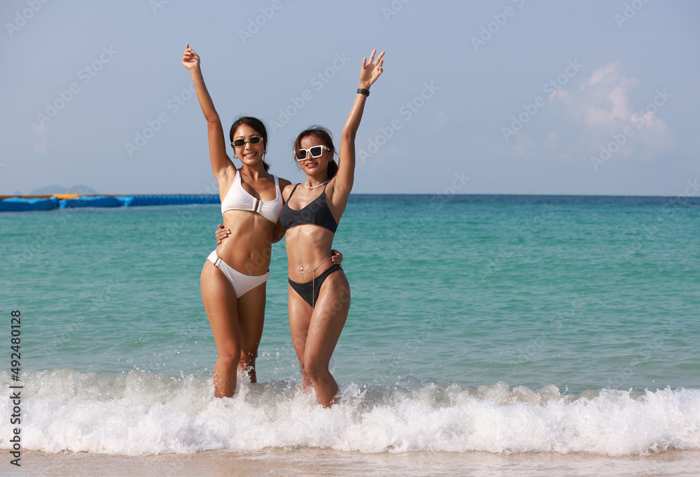Couple Tanned women wearing bikini hand to hand walk to the sea, LGBT and summer vacation concept , Portrait sexy tanned woman hug and hand up on tropical beach Couple Tanned women wearing bikini hand to hand walk to the sea, LGBT and summer vacation concept , Portrait sexy tanned woman hug and hand up on tropical beach