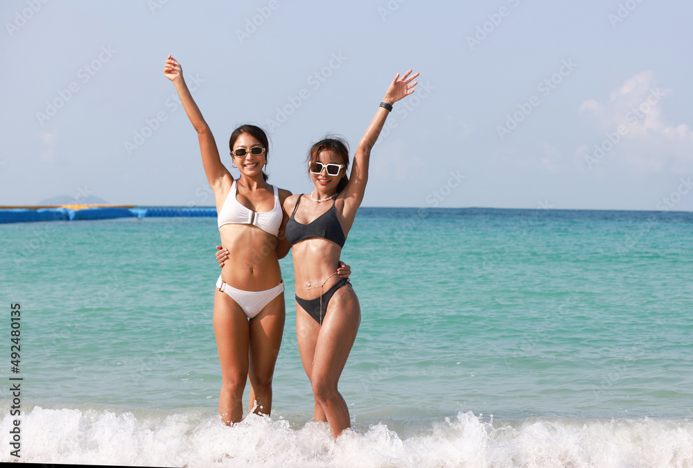 Couple Tanned women wearing bikini hand to hand walk to the sea, LGBT and summer vacation concept , Portrait sexy tanned woman hug and hand up on tropical beach Couple Tanned women wearing bikini hand to hand walk to the sea, LGBT and summer vacation concept , Portrait sexy tanned woman hug and hand up on tropical beach