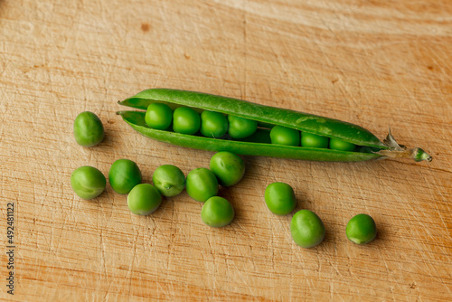 Green fresh pea pods and peas on wooden background, top view