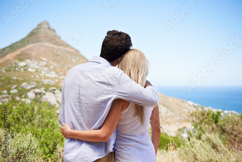 Sharing a glorious view. Rear view of a young couple embracing as they enjoy a view of the mountainside.