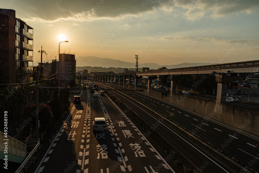 Naklejka premium 夕陽の差す街並みと「速度落とせ」の道路標示