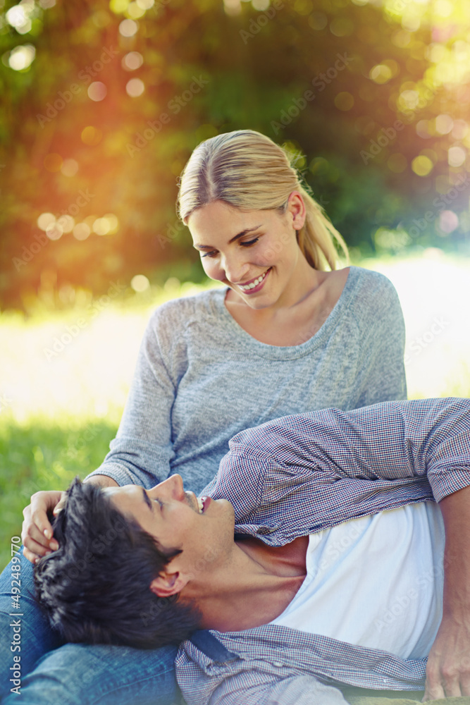 Love just fell into her lap. Shot of a happy young couple lying on the grass and sharing an affectionate moment together.