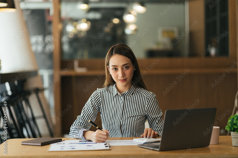 Beautiful asian woman working at the office in the evening,Thailand worker writing book in the company
